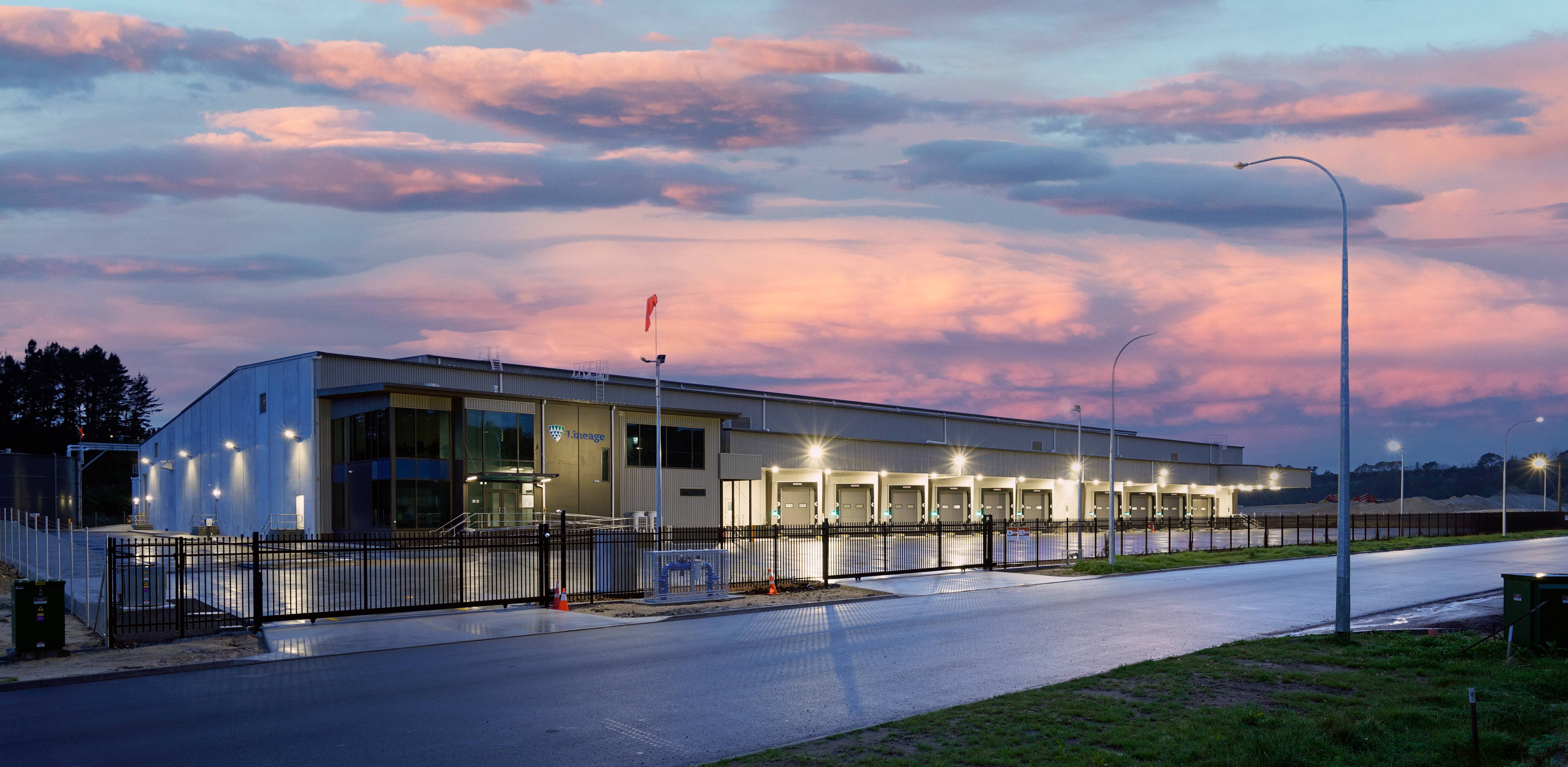 El nuevo almacén de temperatura controlada de Lineage en Tauriko, Tauranga, Nueva Zelanda, se ilumina con un espectacular amanecer. El cielo, en tonos rosas, naranjas, morados y azules, ofrece un impresionante telón de fondo para el nuevo almacén.