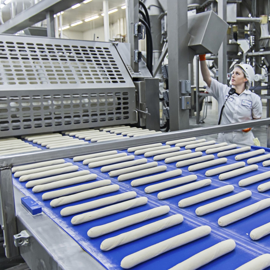 Worker behind a conveyor belt of dough
