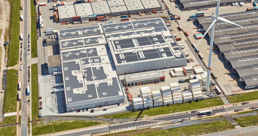 Vue aérienne d’un entrepôt frigorifique avec panneaux solaires et éolienne en Belgique