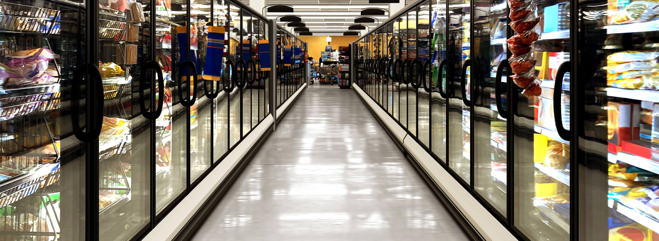 Frozen food aisle in a grocery store featuring glass-door freezers stocked with packaged meals and frozen goods.