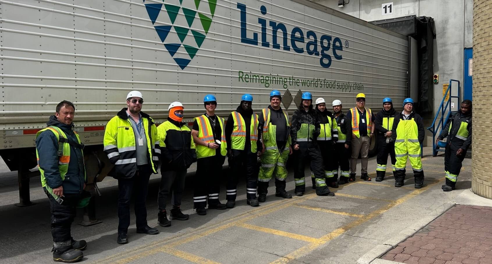 Miembros del equipo de almacén de Calgary Great Plains juntos delante de un remolque de Lineage , mostrando una sólida cultura de seguridad y unidad de equipo.