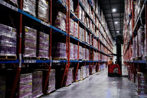 Interior de un almacén frigorífico de Lineage con estanterías, palés y una carretilla elevadora a la vista.