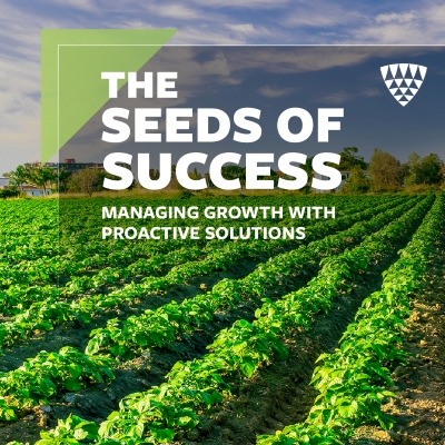 Green crop field under a clear sky with bold text reading “The Seeds of Success: Managing growth with proactive solutions.”