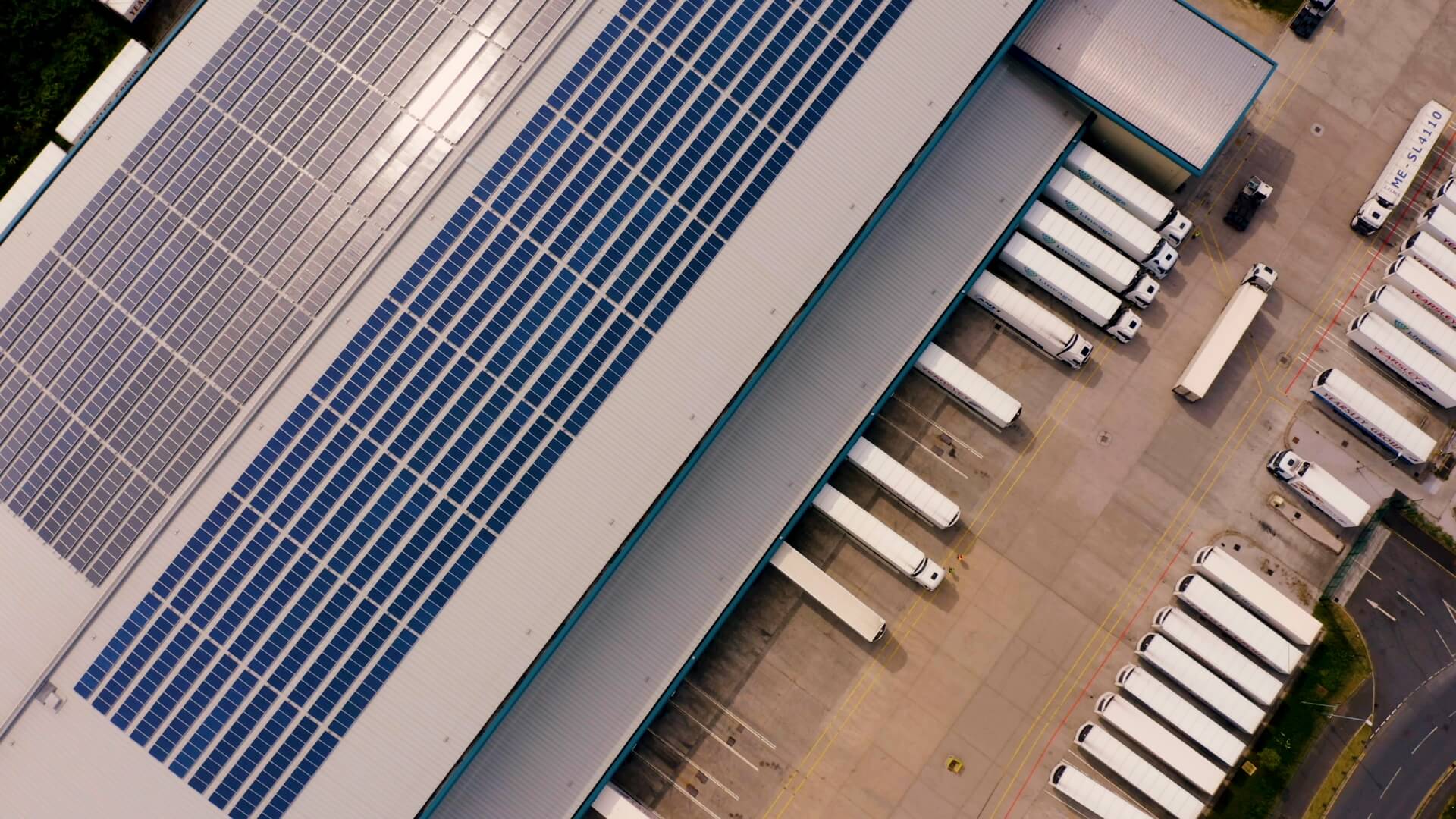 Vista aérea de un almacén frigorífico de Lineage en el Reino Unido con paneles solares en el tejado y camiones en los muelles de carga.