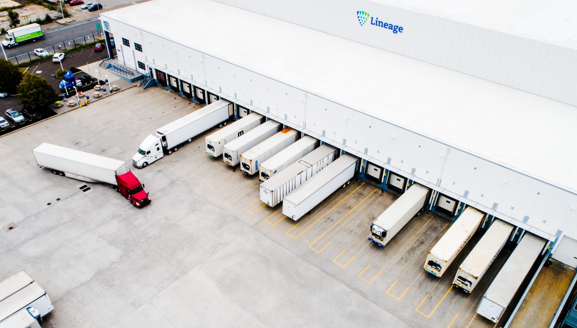 Aerial view of refrigerated trucks loading and unloading at a Lineage warehouse, showcasing foodservice distribution and cold chain operations.