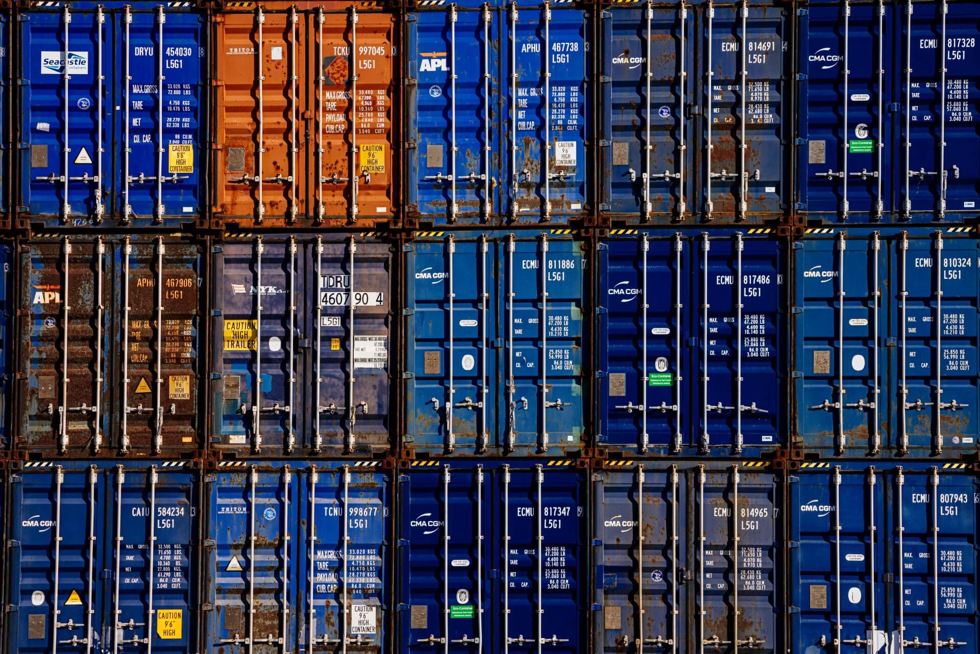 Stacked shipping containers at a busy port terminal, representing U.S. food exports, global trade logistics and temperature-controlled ocean freight movement.