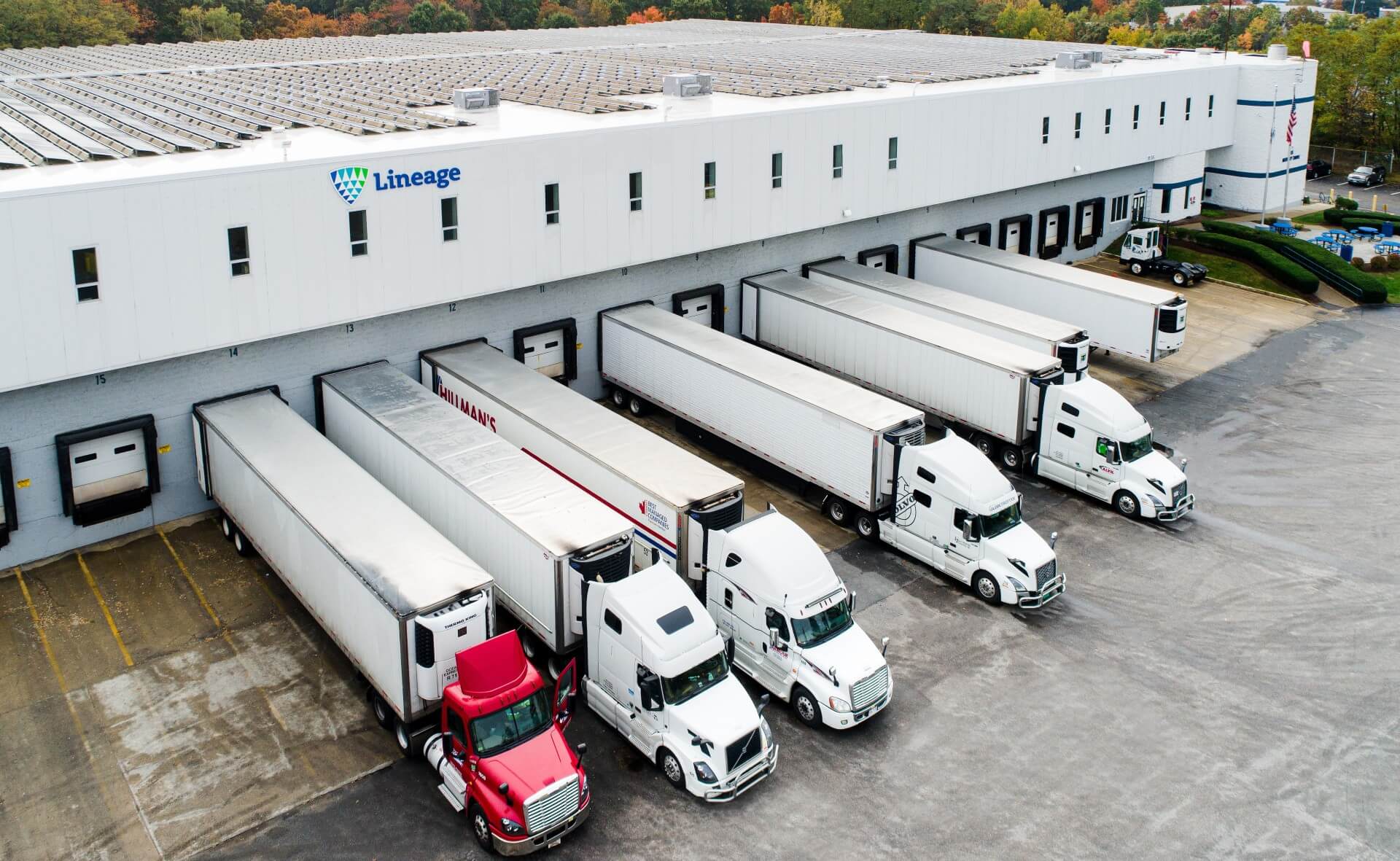 Lineage temperature-controlled warehouse with trucks loading at dock doors for cross-border logistics operations
