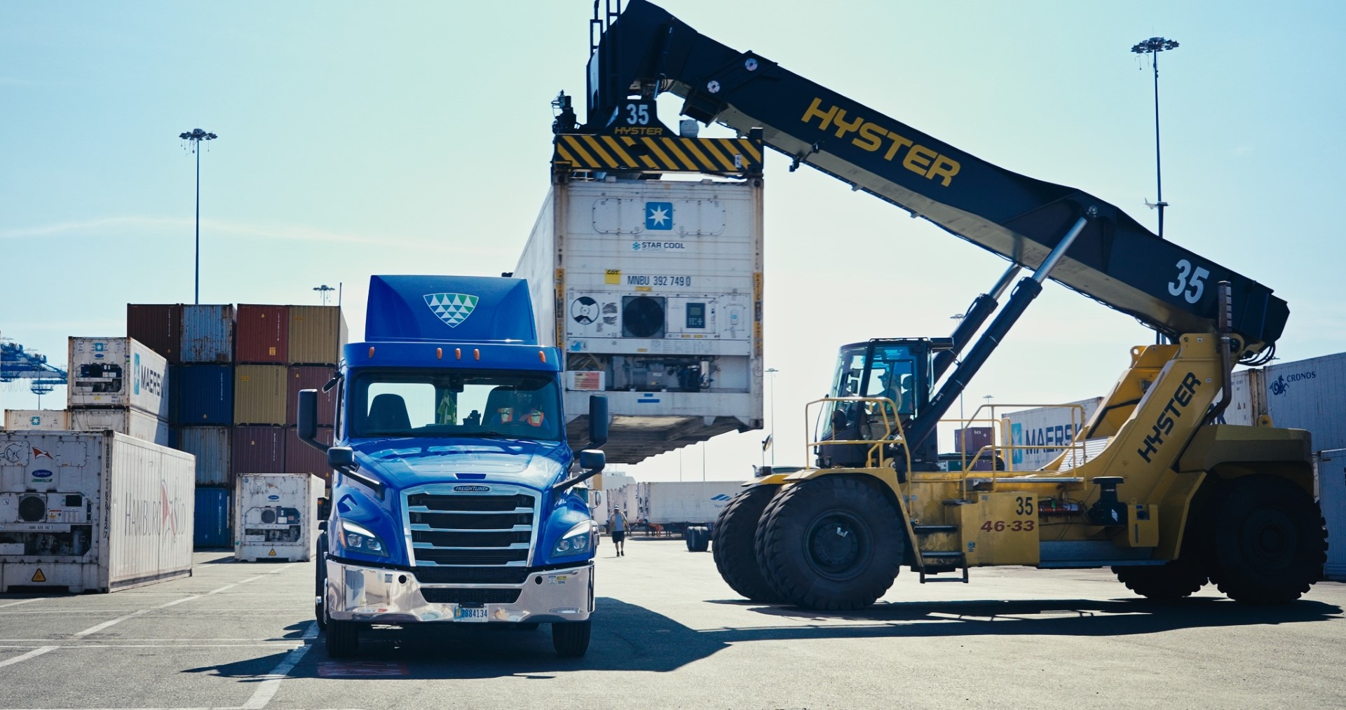 Lineage frigorífico Lineage que transporta un contenedor en una terminal portuaria, con maquinaria de manipulación de carga que presta apoyo a las operaciones de transporte de mercancías bajo control aduanero.