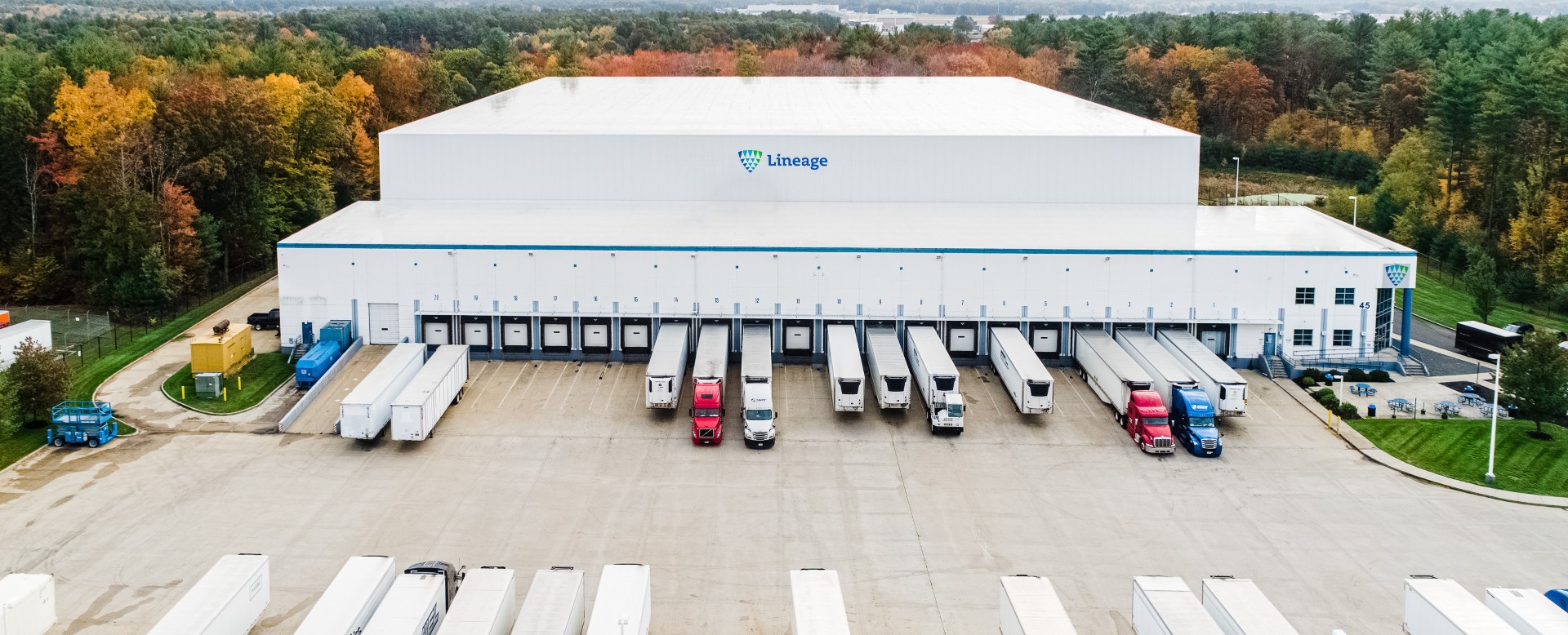 Aerial view of a Lineage cold storage warehouse with multiple semi-trailers at loading docks, supporting managed transportation and integrated cold chain logistics.