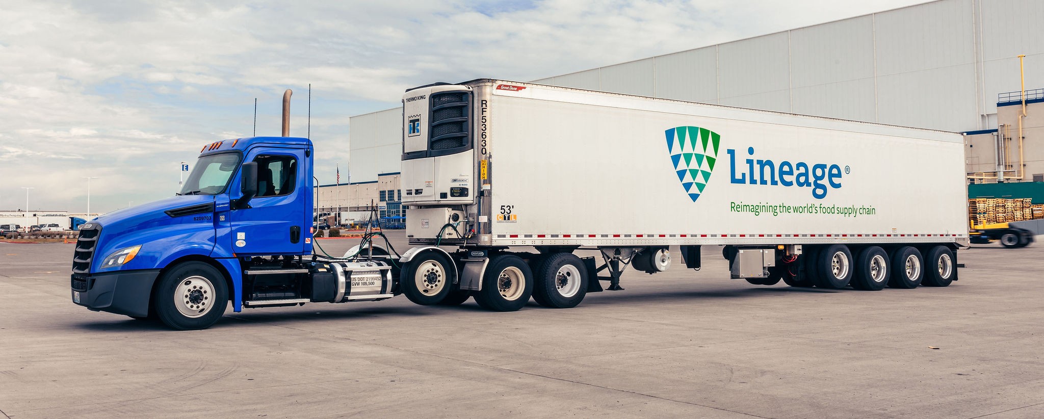 Lineage refrigerated truck and temperature-controlled trailer outside a cold storage facility.