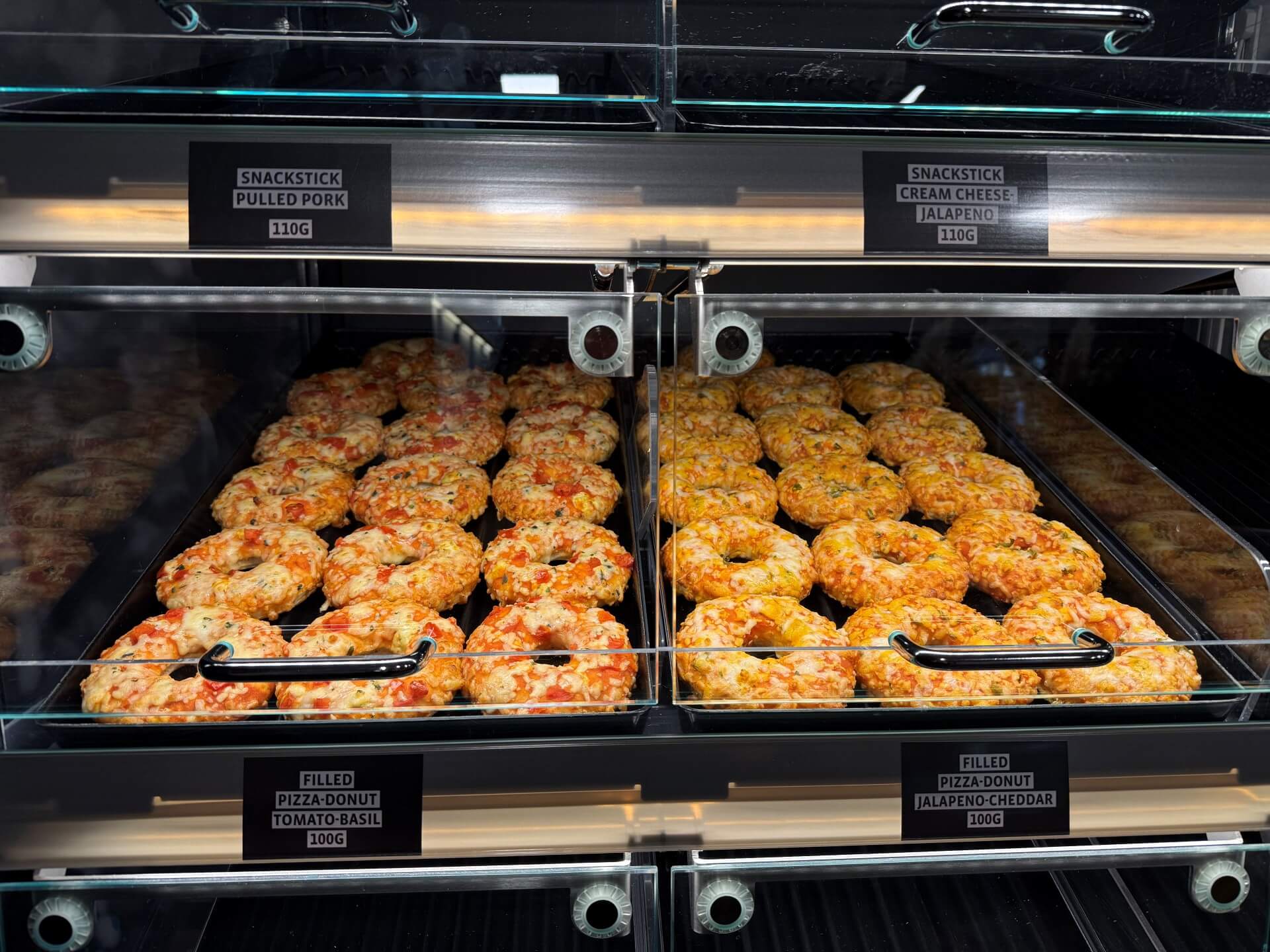 Display case filled with frozen stuffed pizza donuts and savory bakery products, illustrating ready-to-bake frozen foods for retail distribution in a commercial foodservice setting.