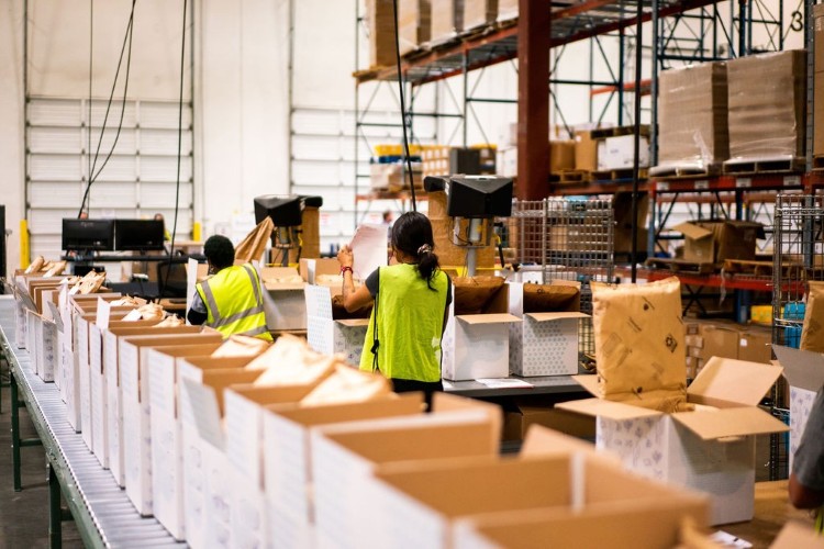 Lineage team members packing temperature-controlled direct-to-consumer orders on a fulfillment line inside a warehouse..