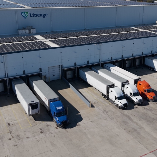 Lineage cold storage warehouse with refrigerated trailers at loading docks, highlighting integrated warehousing and transportation solutions for frozen food distribution.