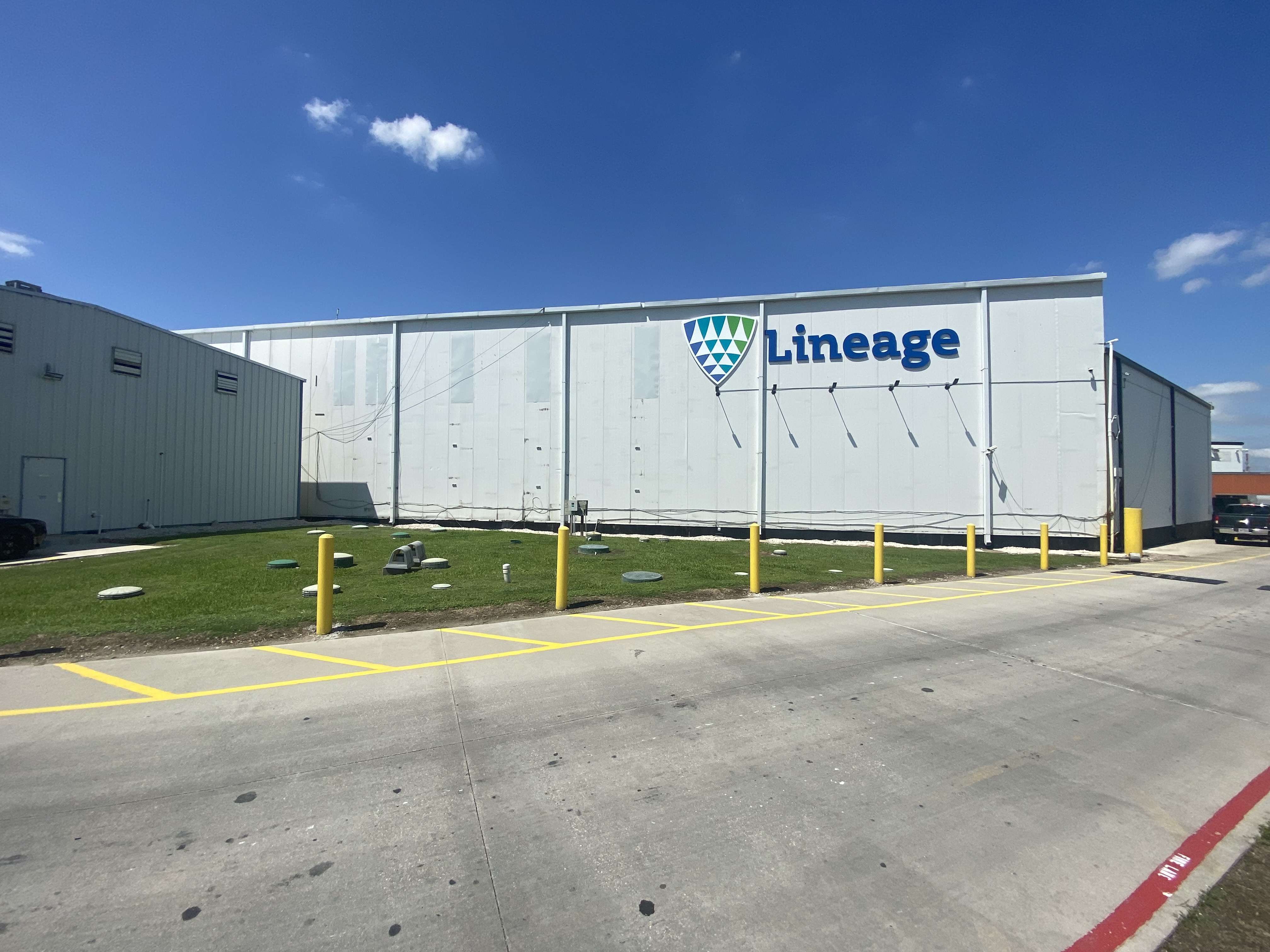 Vue extérieure de Lineagede Houston, près de l’autoroute 225 à La Porte, au Texas, avec un grand entrepôt blanc avec une marque bien en vue et une aire de chargement sécurisée et spacieuse.