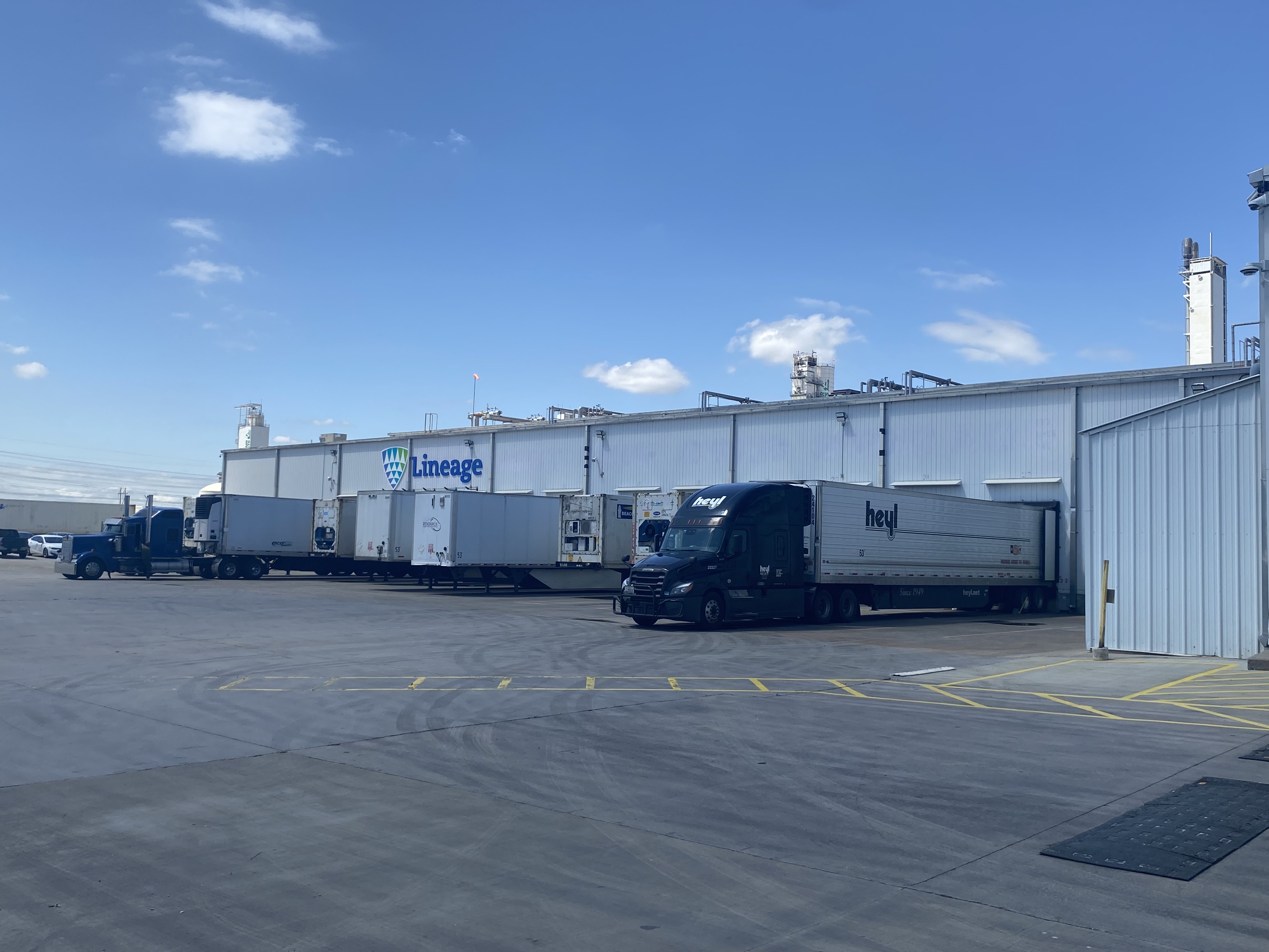 Lineageavec plusieurs camions et remorques sur les quais de chargement, présentant des opérations efficaces et une infrastructure logistique avancée de la chaîne du froid.