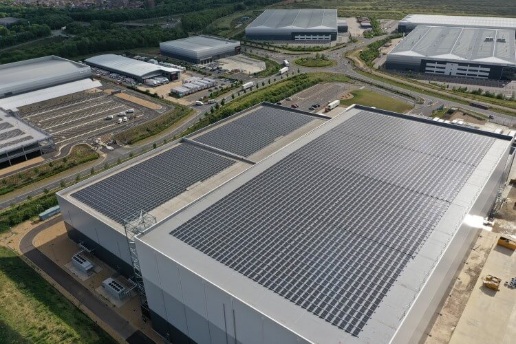 Almacén frigorífico de Lineageen Peterborough con paneles solares, muelles de carga y camiones de marca.