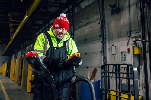 Lineage Bolingbrook team member smiling while using handheld warehouse technology inside a cold storage facility.