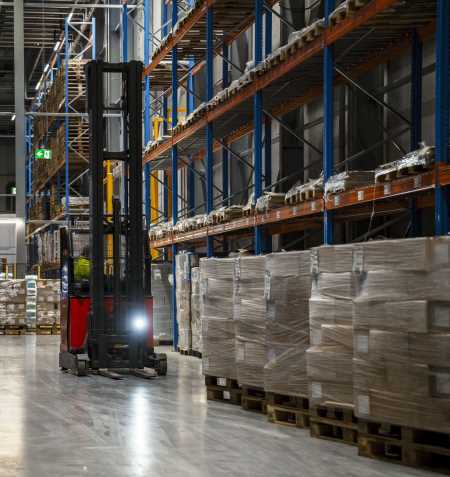 A Lineage team member works inside a cold storage warehouse in Bremerhaven, using a forklift to move pallets of frozen food inside the warehouse.