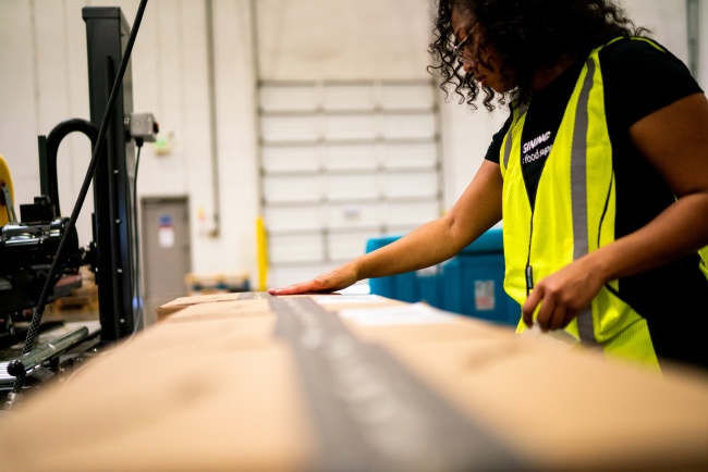 Lineage team member preparing and sealing a direct-to-consumer order at a fulfillment station.
