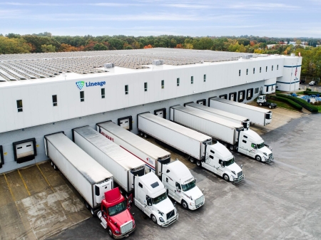 Lineage warehouse with refrigerated trucks docked for loading and distribution, representing foodservice logistics and cold chain efficiency.