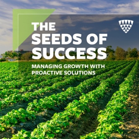 Green crop rows stretching across a farm field under a blue sky, representing agricultural growth and proactive supply chain solutions featured in the Seeds of Success campaign.