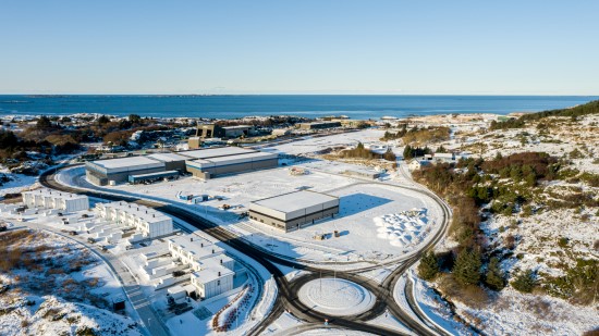 Aerial view of the Lineage cold storage facility in Haugesund, Norway, showing multiple temperature-controlled warehouses near the coastline and surrounding snowy landscape.
