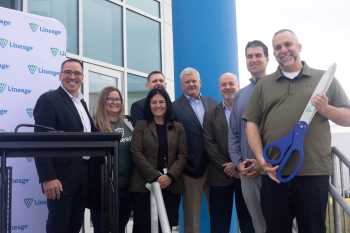 A group of Lineage team members stand with a large pair of blue scissors before the ribbon cutting