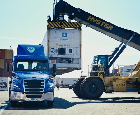 Lineage truck and container handling equipment loading a refrigerated shipping container at a port facility.