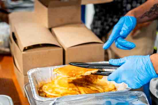 Un voluntario Lineage ayuda a distribuir alimentos en un acto