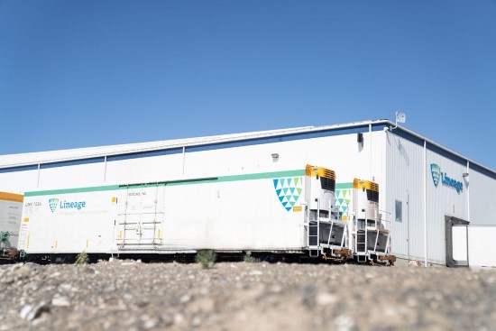 Temperature-controlled Lineage railcar positioned outside a Lineage facility, with two refrigeration units visible on the end of the railcar and a clear blue sky overhead.