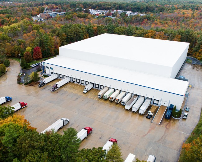 Aerial view of a Lineage cold storage facility in Massachusetts with trucks and trailers positioned at multiple loading docks.