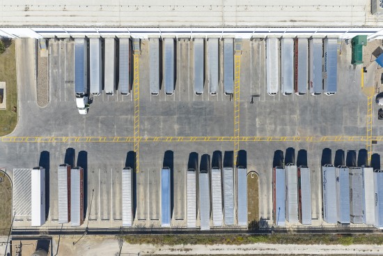 Overhead aerial view of trailers positioned at loading docks outside a Lineage cold storage warehouse, illustrating transportation operations and distribution across the cold chain.