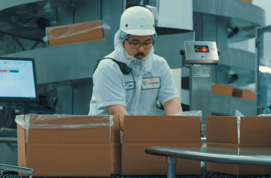 A Lineage team member packs boxes on a production line, supporting foodservice and packaging operations.