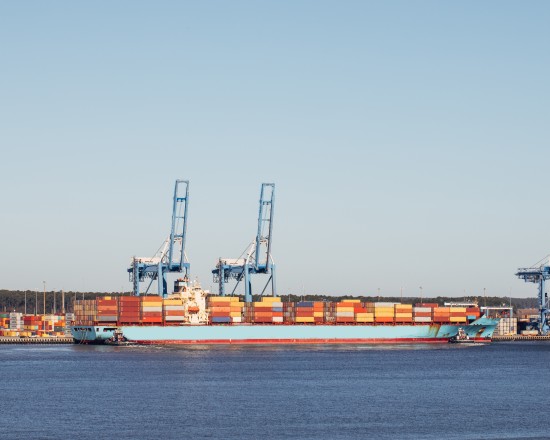Container ship docked at a port with cranes loading cargo, representing ocean freight transport