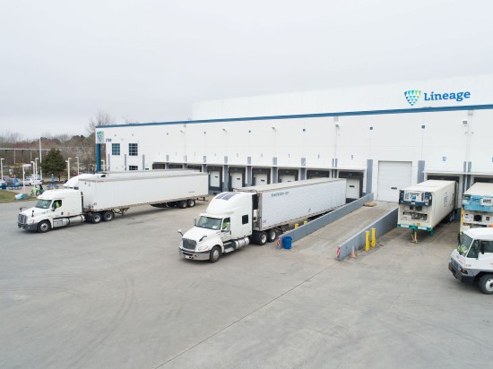 Refrigerated trucks at loading docks outside a Lineage cold storage warehouse.