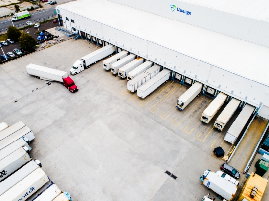 Aerial view of Lineage cold storage facility with multiple semi-trucks at loading docks, representing integrated transportation and warehousing services.