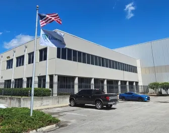 Exterior view of Lineage’s Dignan cold storage facility in Jacksonville, Florida, showcasing the modern building design and prominently displayed flags under a clear blue sky.