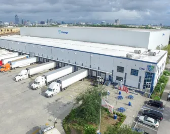 Exterior del almacén frigorífico West Beaver de Lineage en Jacksonville con varios camiones en los muelles de carga, bajo un cielo nublado. 