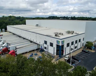 Vue extérieure de LineageCollege Park à Atlanta, présentant un entrepôt moderne avec plusieurs quais de chargement et un grand stationnement pour camions.