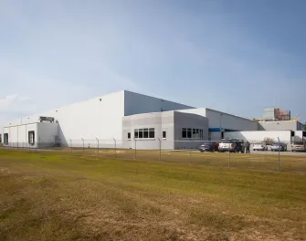 Exterior view of Lineage’s Macon cold storage facility in Atlanta, Georgia, featuring a white warehouse with loading docks, fenced perimeter, and a small office area.