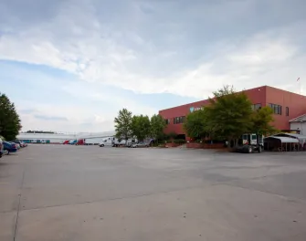Exterior view of Lineage’s McDonough - 200 King Mill cold storage facility, featuring a red-brick office building, spacious parking lot, and multiple docked trucks.