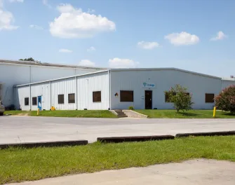 Exterior view of Lineage’s Unadilla cold storage facility near Atlanta, Georgia, featuring a white warehouse with a small office entrance, parked truck, and surrounding greenery.