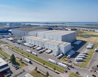 Vue aérienne de Lineage's Bergen op Zoom, installation d’entreposage frigorifique aux Pays-Bas, comprenant plusieurs quais de chargement et camions réfrigérés pour le factage et la distribution.