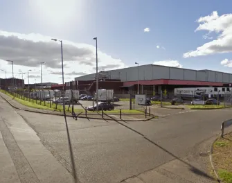 Vue de rue de Lineagede Bellshill en Écosse avec des camions de marque Yearsley Group et un accès sécurisé.