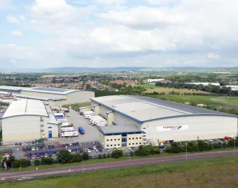 Vue aérienne de Lineageà Heywood, au Royaume-Uni, avec des camions du groupe Yearsley et plusieurs bâtiments répartis sur un grand site logistique.
