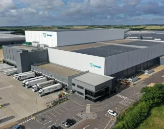 Vue aérienne de LineageEntrepôt frigorifique de Peterborough avec panneaux solaires sur le toit, entouré de bâtiments industriels et de routes modernes.