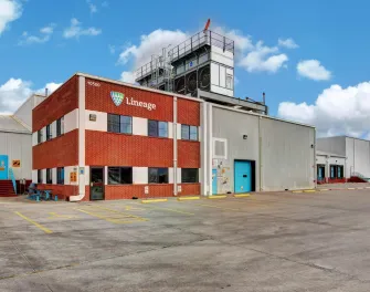 Extérieur de la Lineage installation de stockage frigorifique à El Paso, Texas, montrant l’immeuble de bureaux en brique, les baies d’entrepôt et le terrain pavé sous un ciel dégagé.