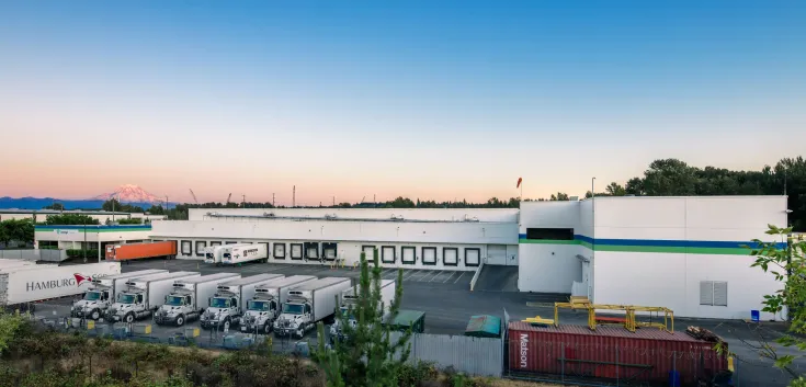 Foto exterior de las instalaciones de Lineage en Tacoma al atardecer con el monte Rainier al fondo.
