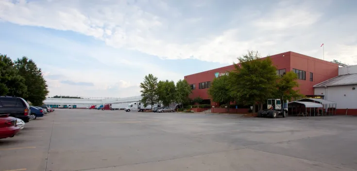 Vue extérieure de LineageMcDonough - Entrepôt frigorifique du 200 King Mill, doté d’un immeuble de bureaux en briques rouges, d’un stationnement spacieux et de plusieurs camions à quai.