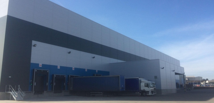 Modern ambient cold storage warehouse with multiple loading docks and trailers at Lineage’s Belle Eau Park facility in Bilsthorpe, UK.